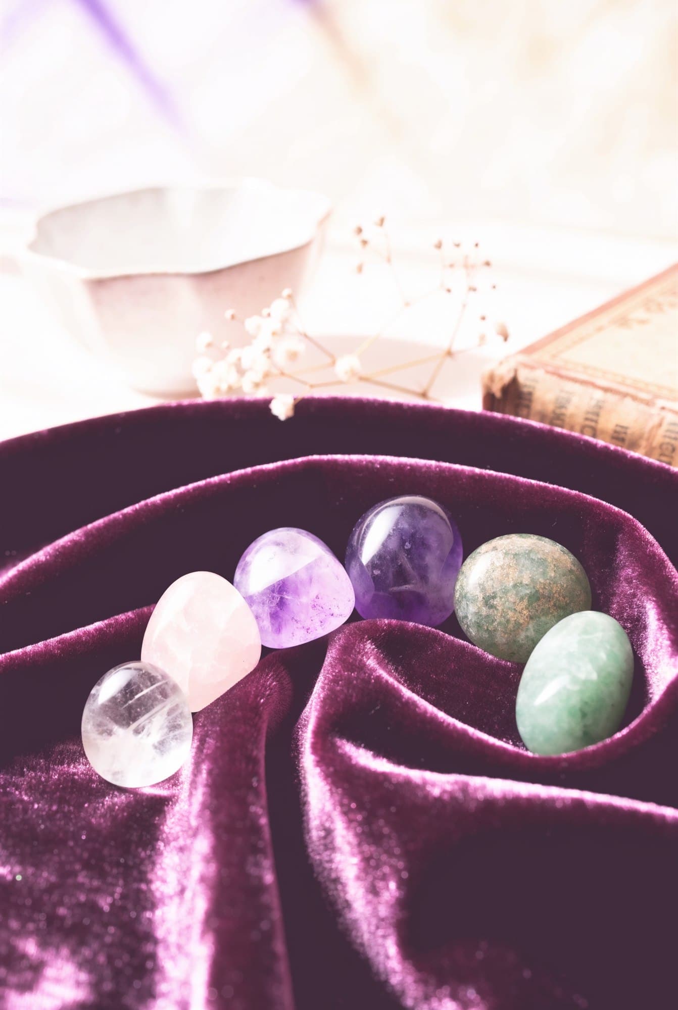 Seven chakra stones arranged in an arc on deep plum velvet